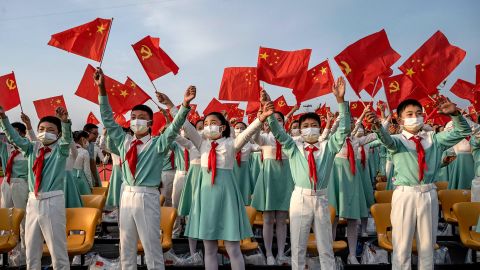 Chinese students wave party and national flags at a ceremony marking the party's centenary on July 1, 2021.