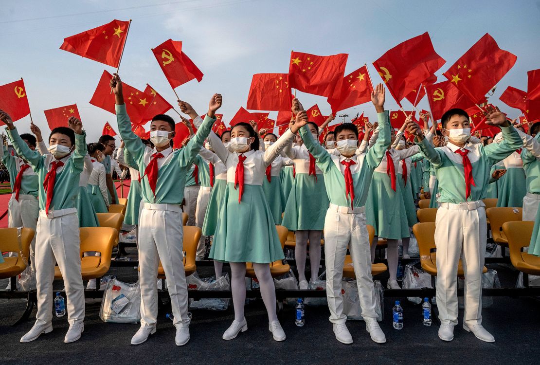 Chinese students wave party and national flags at a ceremony marking the party's centenary on July 1, 2021.