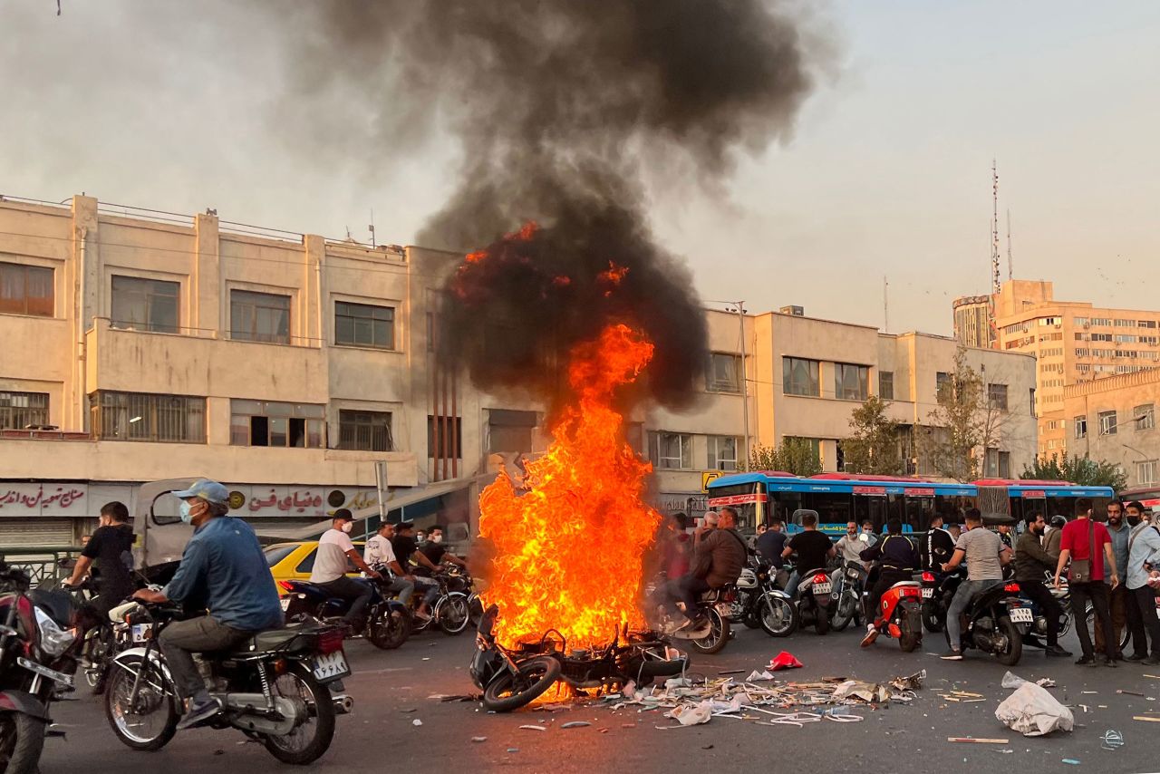 People gather next to a burning motorcycle in Tehran, Iran, on Saturday, October 8. Nearly a month after the start of <a href="https://www.cnn.com/2022/10/13/middleeast/iran-protests-national-uprising-cmd-intl" target="_blank">nationwide protests,</a> parts of Iran now bear the hallmarks of battle zones, with flares lighting up skies, gunfire ringing out and bloody scenes recorded in video footage. The protests were first ignited by the death of 22-year-old Mahsa Amini, who died nearly one month ago after being detained by the country's morality police. But demonstrators have since coalesced around a range of grievances with Iran's regime.