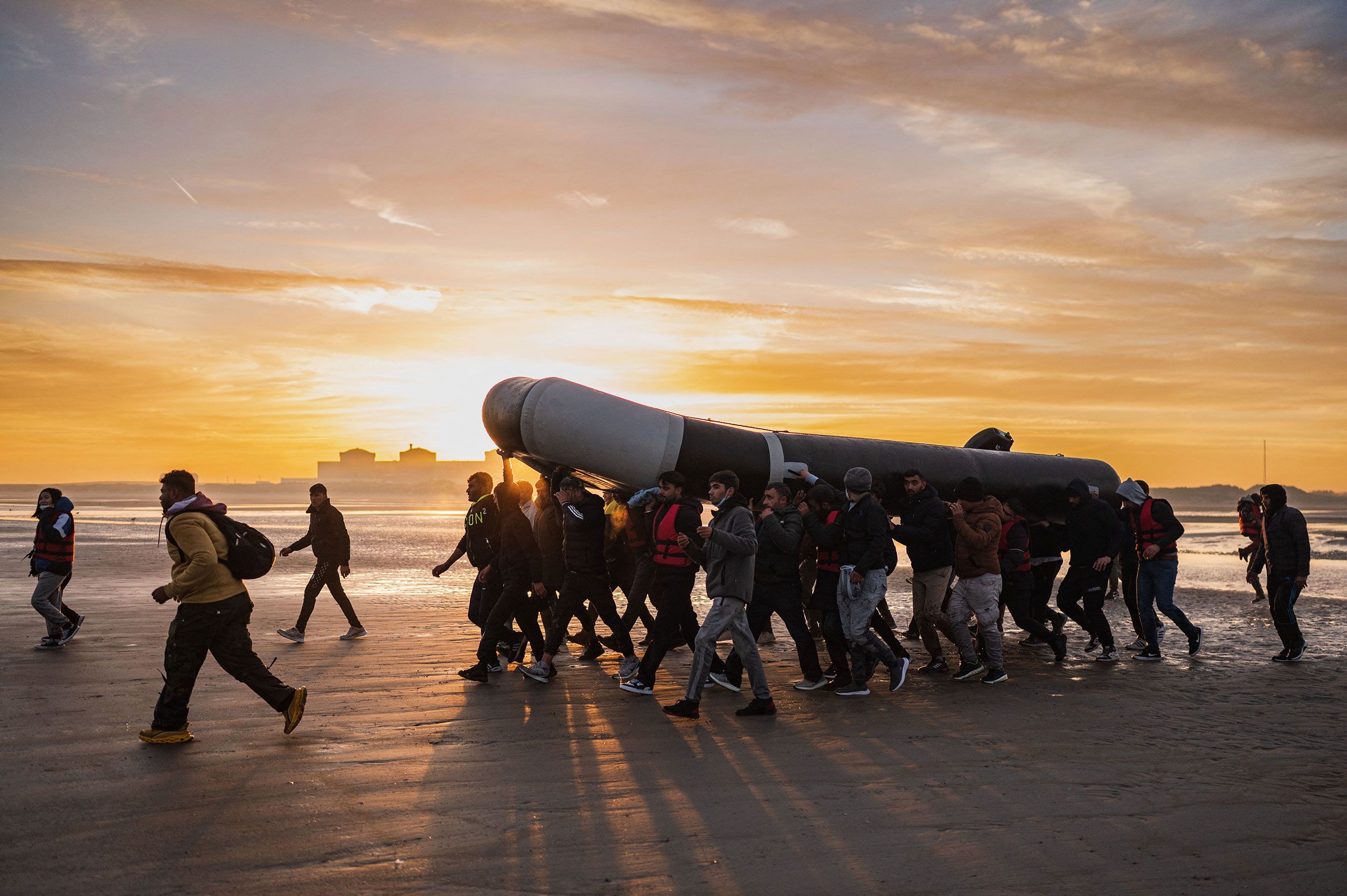 Migrants carry a boat on the beach of Gravelines, France, preparing to cross the English Channel.