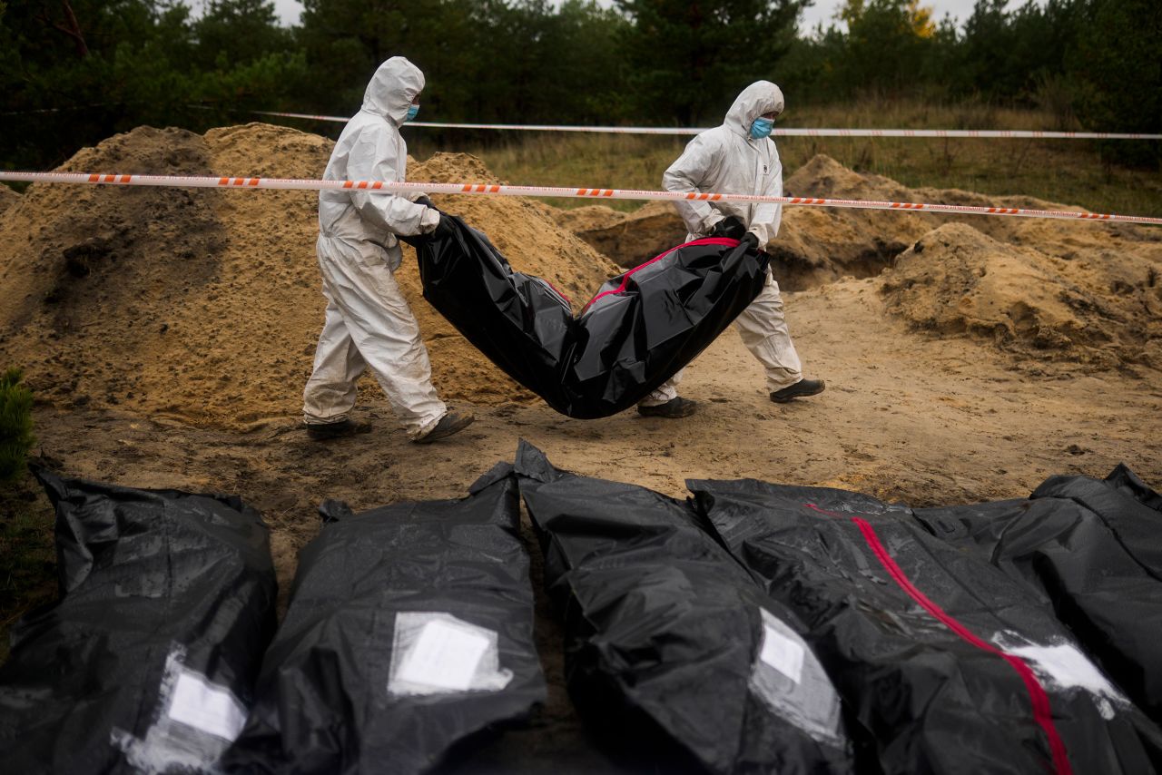 Members of a forensics team carry a body bag as they exhume bodies from a mass grave in Lyman, Ukraine, on Tuesday, October 11. <a href=