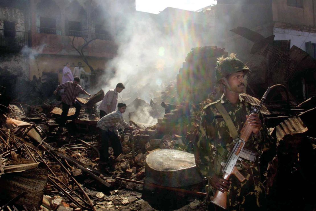 An Indian Muslim family looks for valuables from their burned home while an Indian army soldier stands guard in the downtown area of Ahmedabad, India, March 3, 2002.