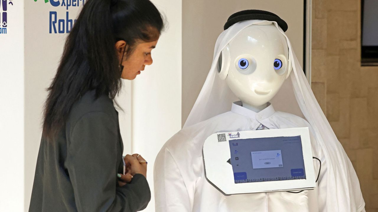 A woman stands near a robot during the GITEX global technology show at the Dubai World Trade Center in Dubai, United Arab Emirates on Wednesday.  