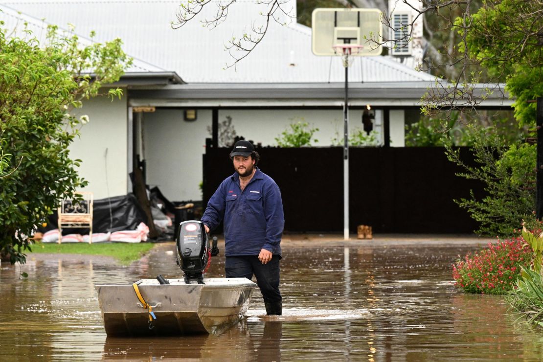 A man pushes a boat as floodwaters inundate a Victorian residential area in Rochester, Australia, October 14, 2022.  