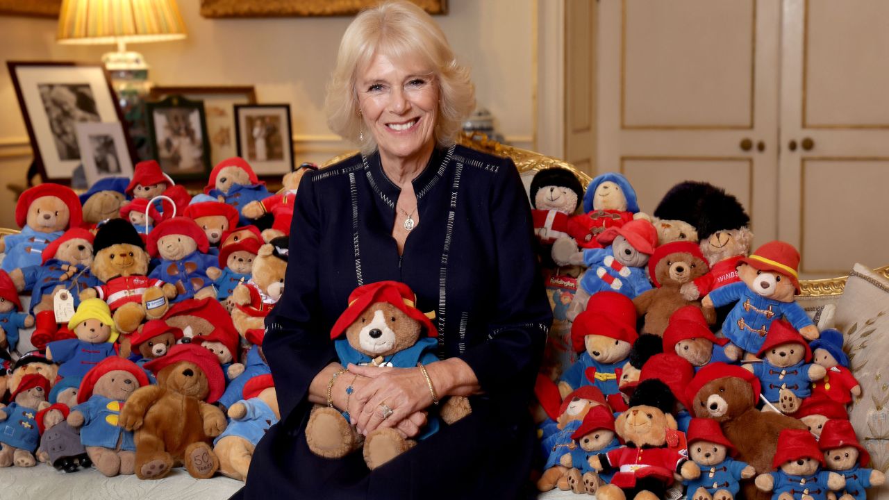 Camilla, Queen Consort, poses on October 13, 2022, with a collection of Paddington stuffed bears on the 64th anniversary of the publication of the first Paddington bear book.