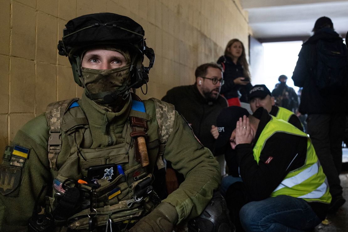 Military and rescue workers take cover as a building in Ukraine's capital is rocked by explosions during an early morning drone attack on October 17.