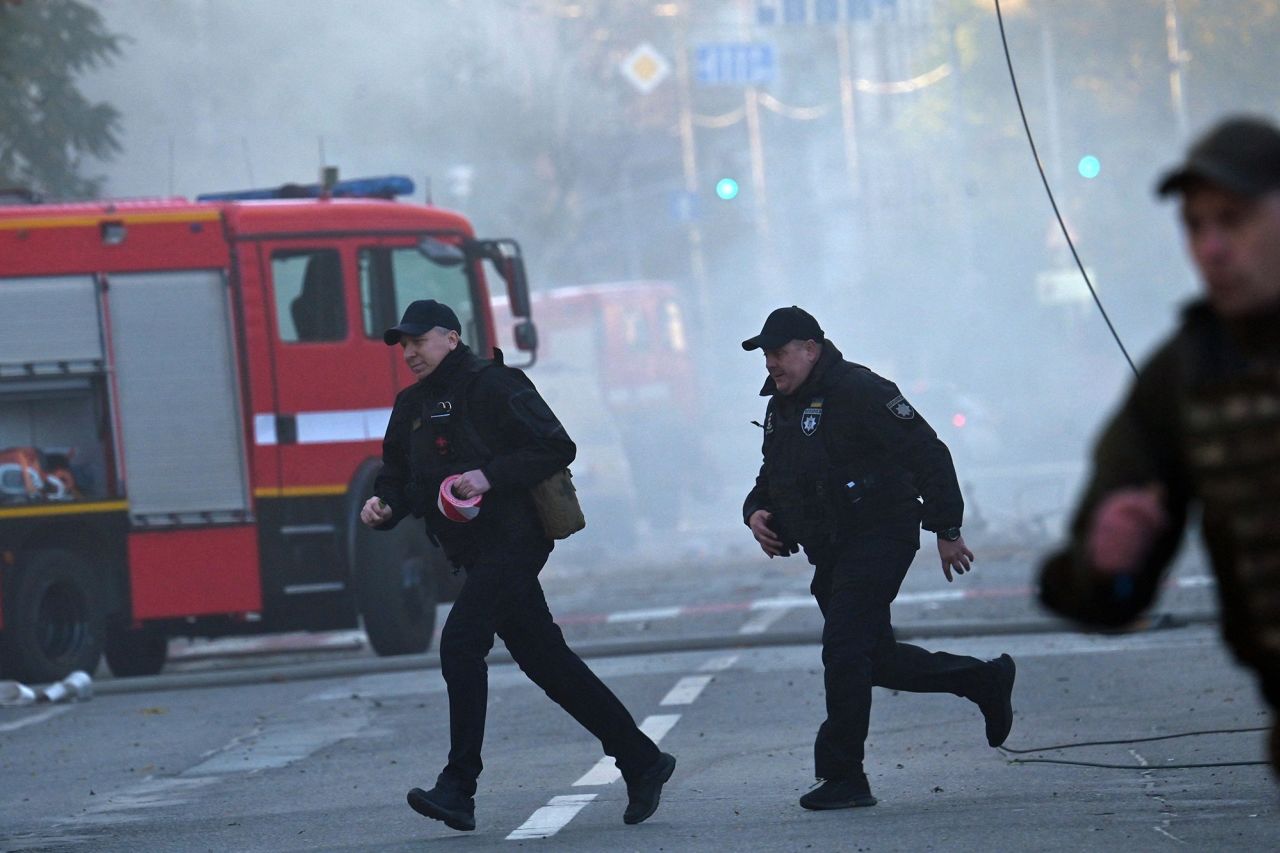 Police officers run after a drone attack in Kyiv on Monday.