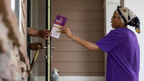 A canvasser for the New Georgia Project hands an informative flyer to a resident in Fairburn, Georgia, on May 12, 2022, while knocking on doors to encourage people to register to vote.