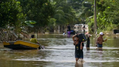 Residents walk through floodwaters in Malaysia's Pahang state on January 8, 2021.