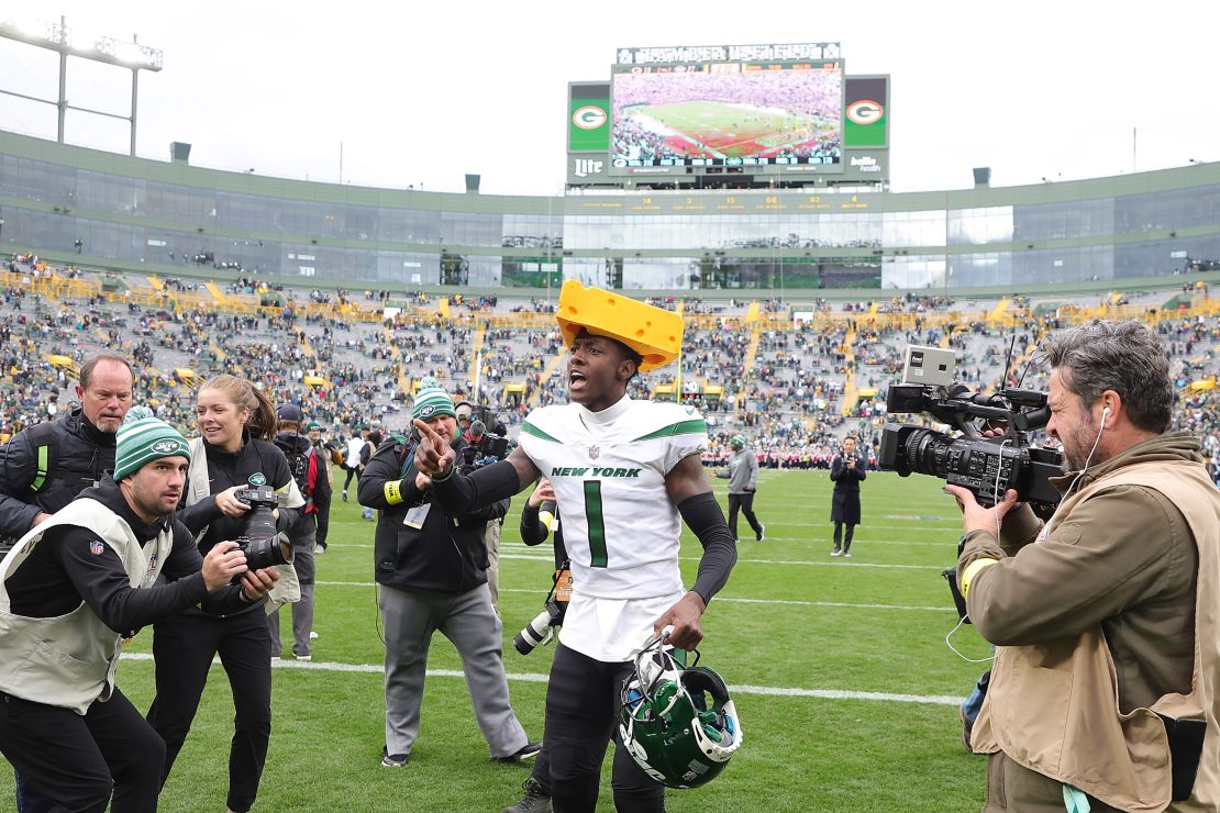 Sauce Gardner of the New York Jets celebrates after beating the Green Bay Packers wearing a cheesehead hat -- a traditional accessory for Packers fans.