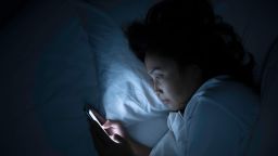 Asian woman play smartphone in the bed at night.