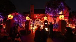 TOPSHOT - People look at a home decorated with pumpkins and ghosts for Halloween, in Burbank, California, October 30, 2021. - Last year's Halloween celebrations were severely curtailed due to the Covid-19 pandemic. (Photo by Robyn Beck / AFP) (Photo by ROBYN BECK/AFP via Getty Images)
