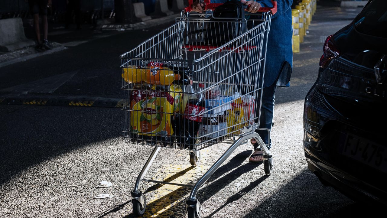 A customer pushes a shopping cart in the parking lot of the Carrefour SA hypermarket in the Grand Littoral retail park in Marseille, France, on Monday, July 25, 2022. 