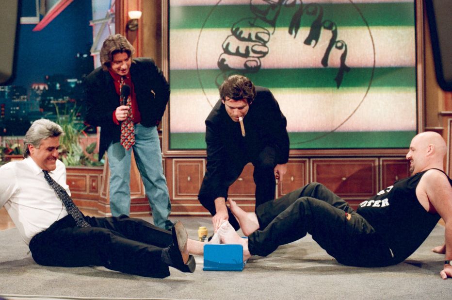 <strong>Toe wrestling:</strong> Since 1976, people from across the world have gathered in Ye Olde Oak Pub in Wetton, England for the Toe Wrestling Championships. Seventeen-time champion Alan "Nasty" Nash is pictured demonstrating his craft with Jay Leno, as Pierce Brosnan watches on. 