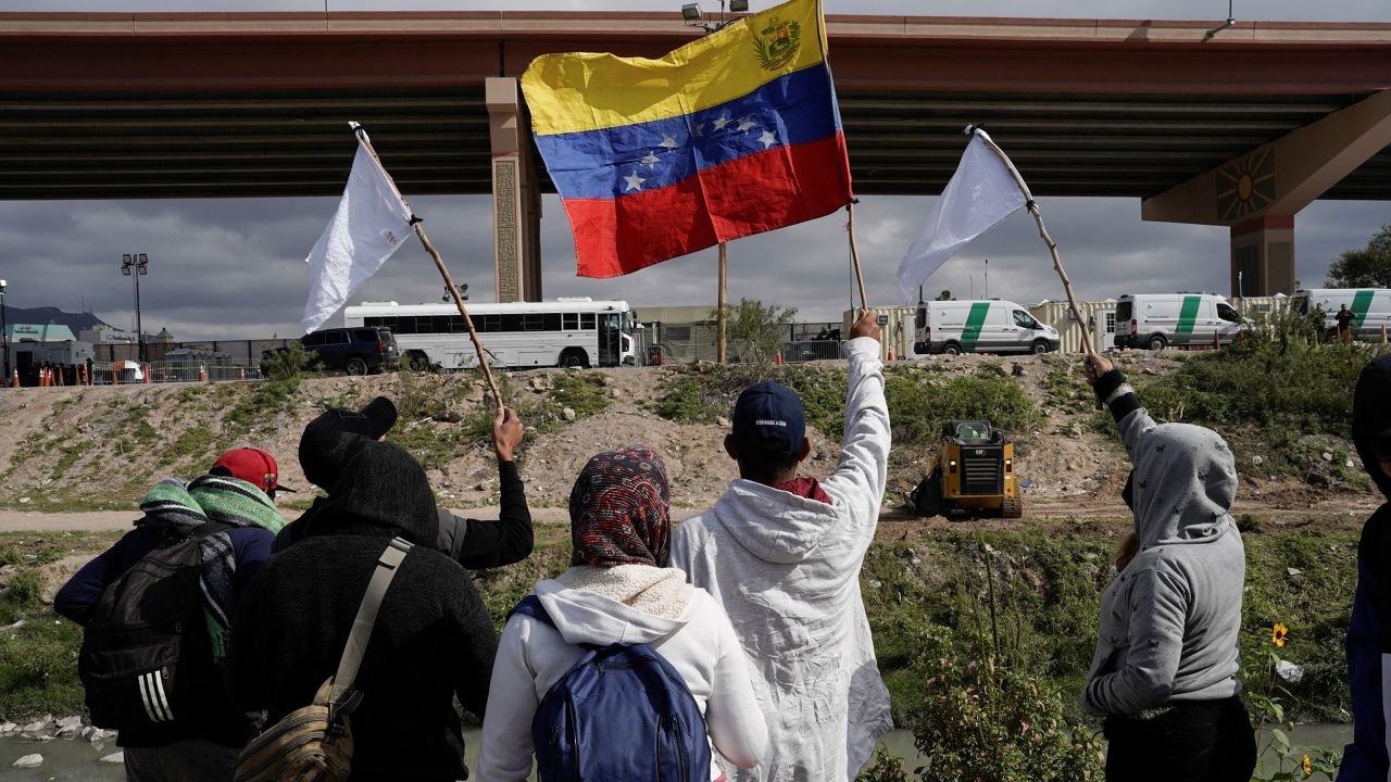Venezuelan migrants wave flags on the banks of the Rio Grande while protesting new US migration enforcement rules in Ciudad Juarez, Mexico, on October 18, 2022. 