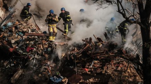 Украинские пожарные работают в разрушенном здании после удара беспилотника в Киеве, 17 октября 2022 года.