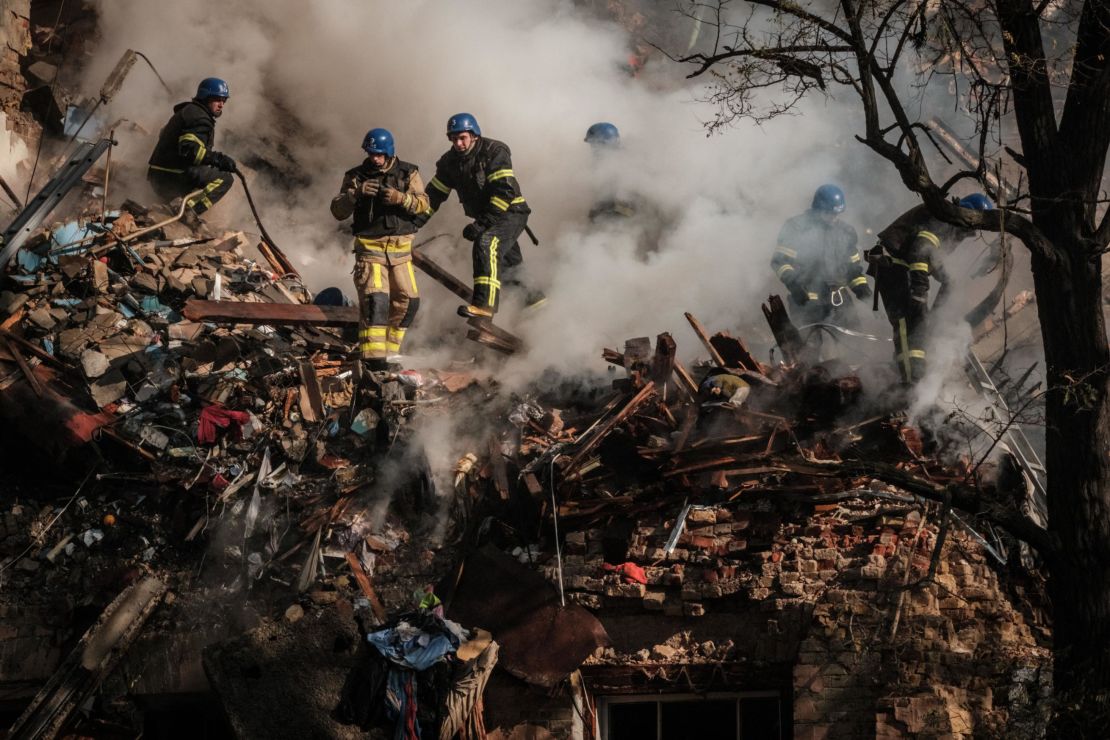 Ukrainian firefighters work on a destroyed building after a drone attack in Kyiv on October 17, 2022.