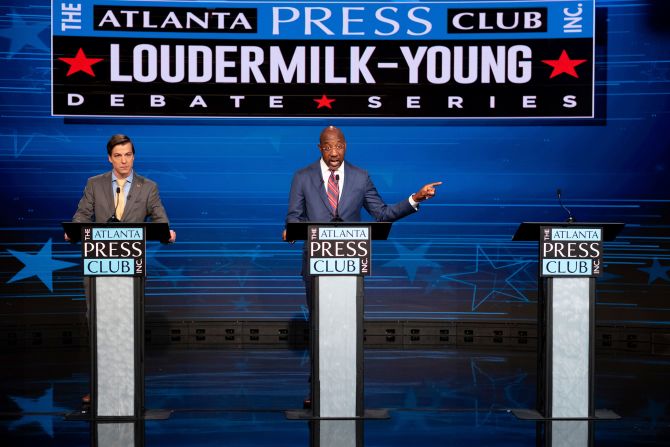Democratic Sen. Raphael Warnock gestures next to an empty podium set up for Republican challenger Herschel Walker, who was invited but did not attend, during a Senate debate with Libertarian challenger Chase Oliver in Atlanta on Sunday, October 16.