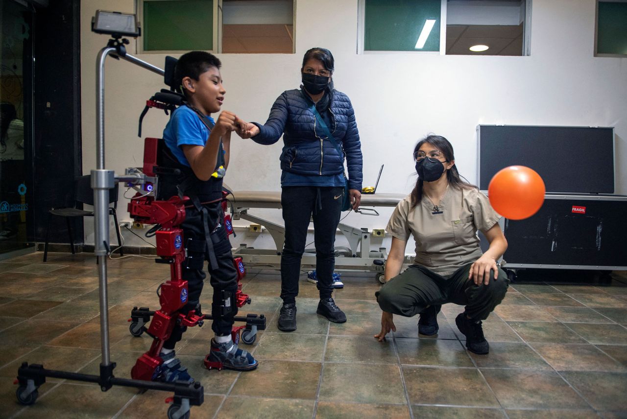 David Zabala, an 8-year-old boy with cerebral palsy, is assisted by a physical therapist and his mother, Guadalupe Cardozo Ruiz, during a rehabilitation session with the robotic exoskeleton Atlas 2030 in Mexico City on Tuesday, October 18.