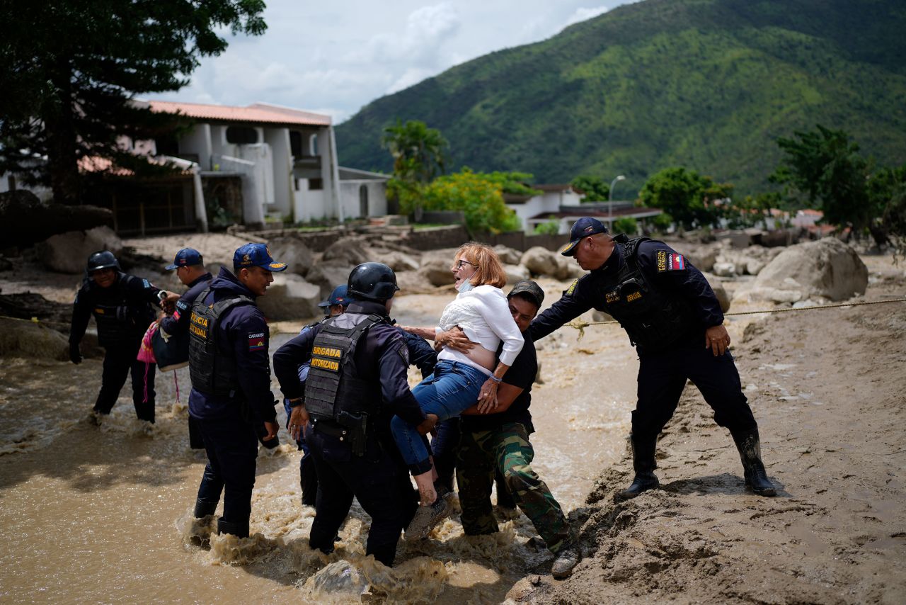 Police carry a woman across a flooded street in El Castano, Venezuela, on Tuesday, October 18.