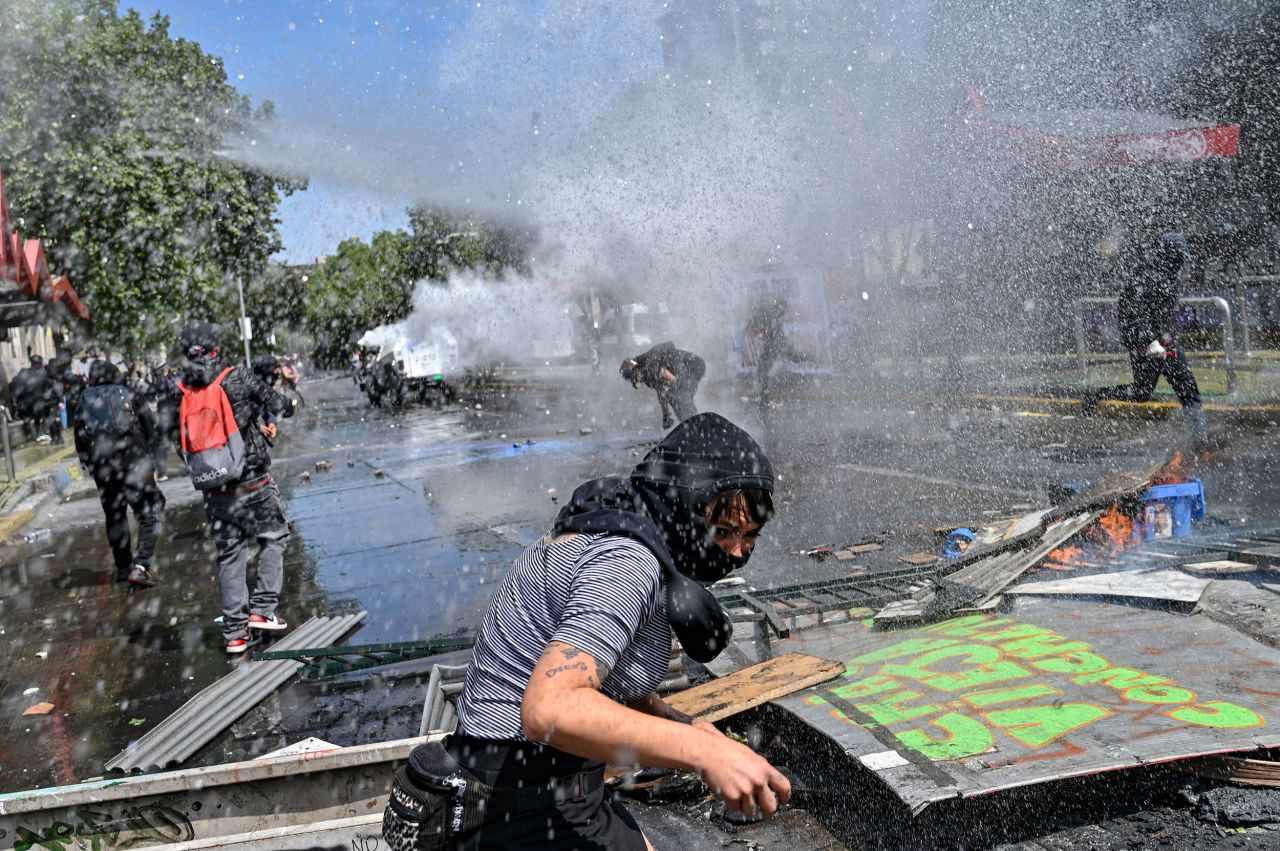 Demonstrators are sprayed with water cannons in Santiago, Chile, during clashes with riot police that erupted on Tuesday, October 18, the third anniversary of a social uprising against rising utility prices.