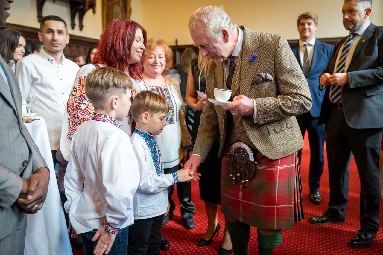 King Charles III shakes hands with a boy in Aberdeen, Scotland, on Monday, October 17, while visiting refugee families from Afghanistan, Syria and Ukraine who have settled in the town.