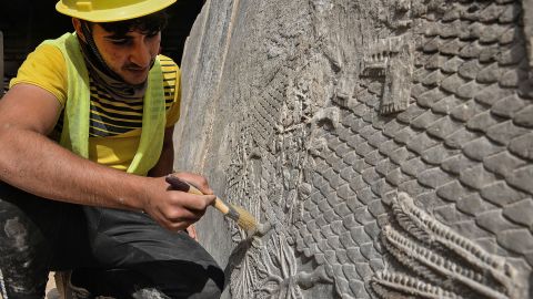 An Iraqi worker excavates a rock-carving relief recently found at the Mashki Gate, one of the monumental gates to the ancient Assyrian city of Nineveh, on the outskirts of what is today the northern Iraqi city of Mosul on October 19, 2022. 