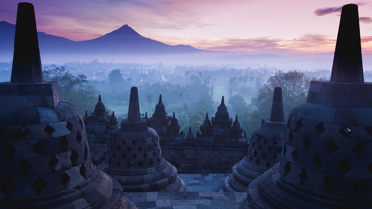 Borobudur is popular at sunrise when travelers can see the breathtaking views of temple's statues and nearby volcanoes from the top of the temple.