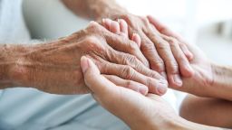 elderly person holding hands with younger person STOCK