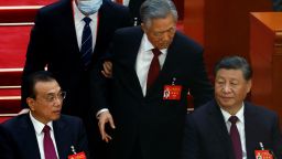 Former Chinese leader Hu Jintao leaves his seat next to leader Xi Jinping and Premier Li Keqiang, during the closing ceremony of the 20th National Congress of the Communist Party of China on Saturday.