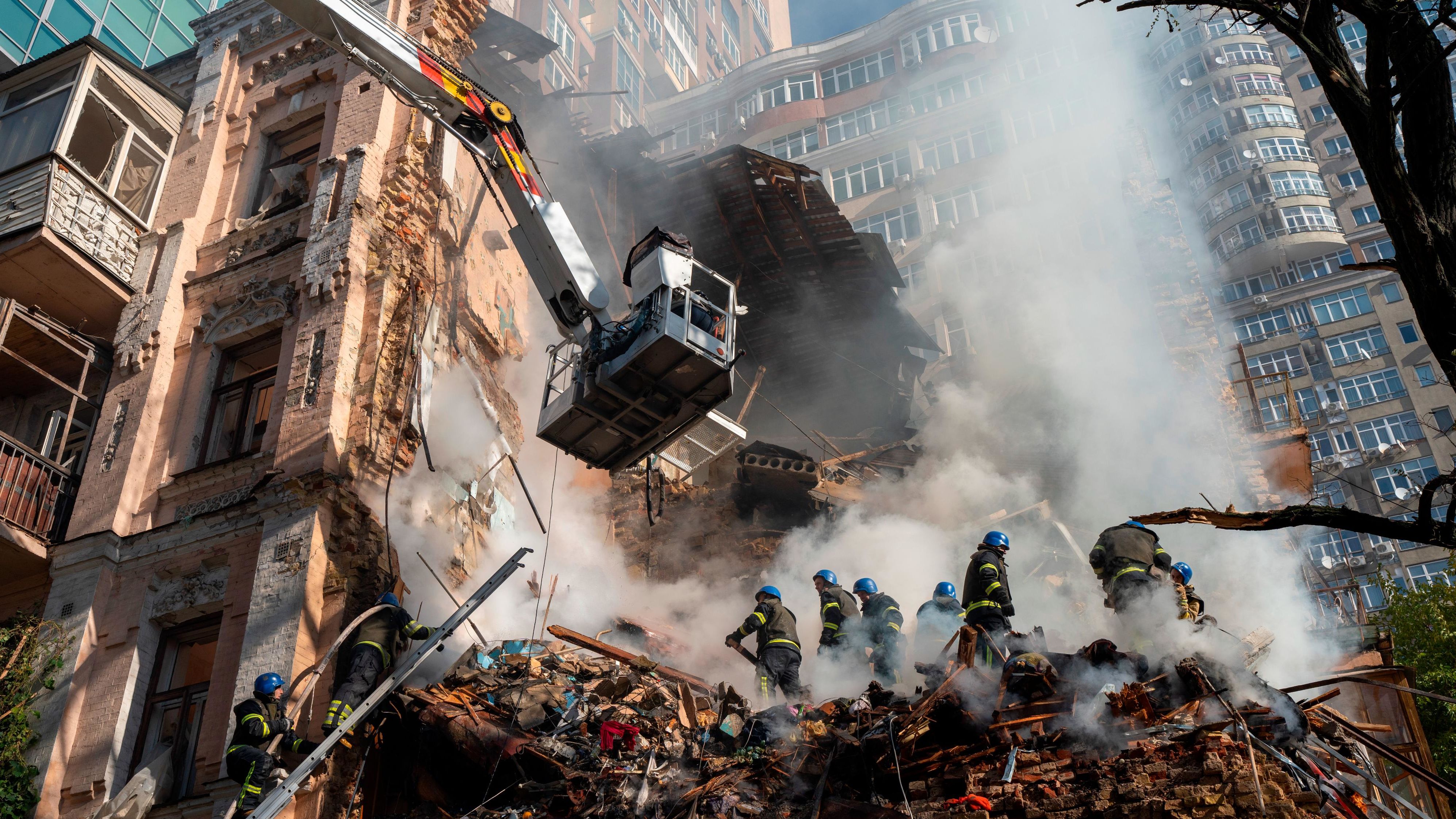 Firefighters work after a drone attack on buildings in Kyiv on October 17, 2022.