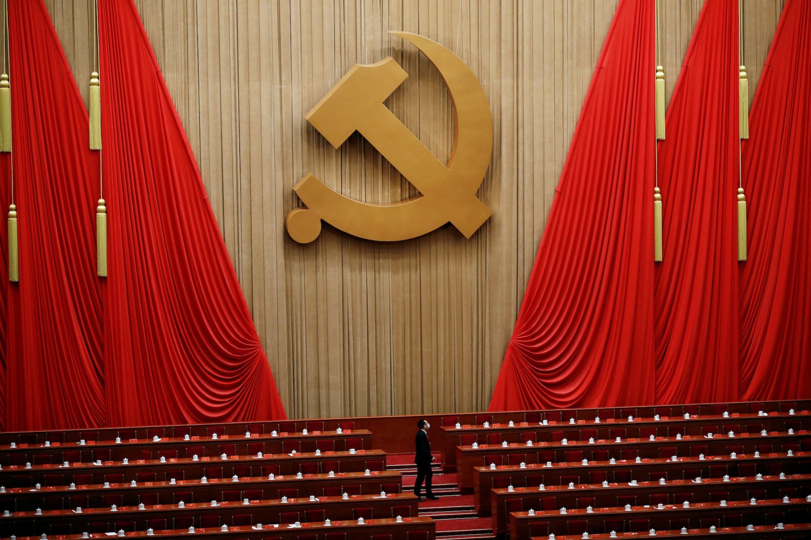A man stands under the Chinese Communist Party emblem at the end of the closing ceremony.