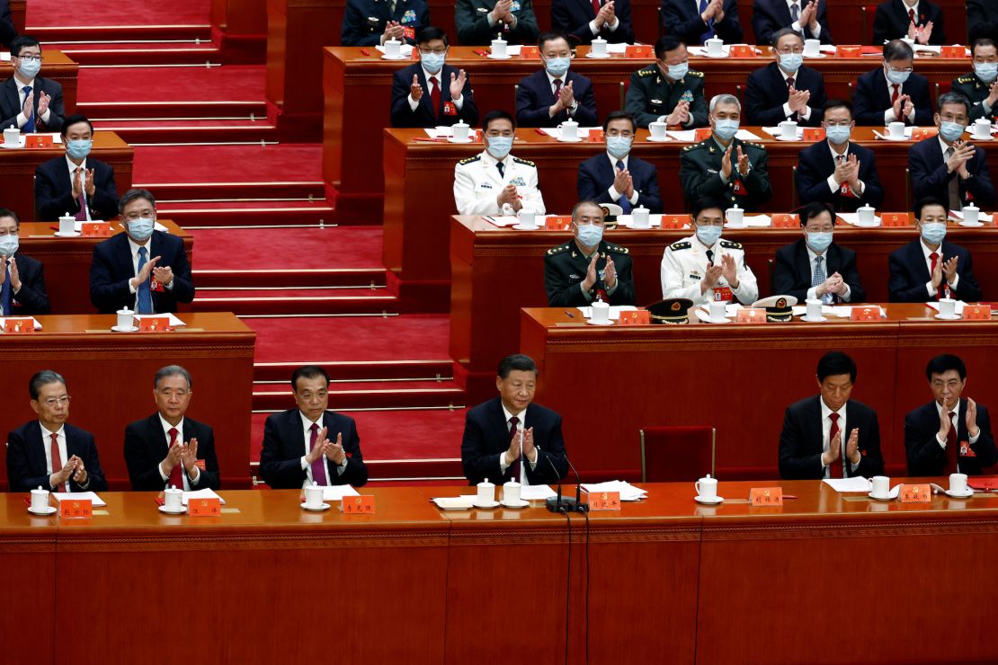 Chinese leader Xi Jinping and other officials applaud during the closing ceremony of the party's 20th National Congress, while the seat occupied by former leader Hu Jintao remains empty, following his unexpected exit from the room.