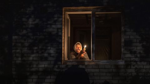 A woman looks out her window during a power outage in Borodyanka, Kyiv region, on October 20. Airstrikes cut power and water supplies to thousands of Ukrainians earlier in the week. 
