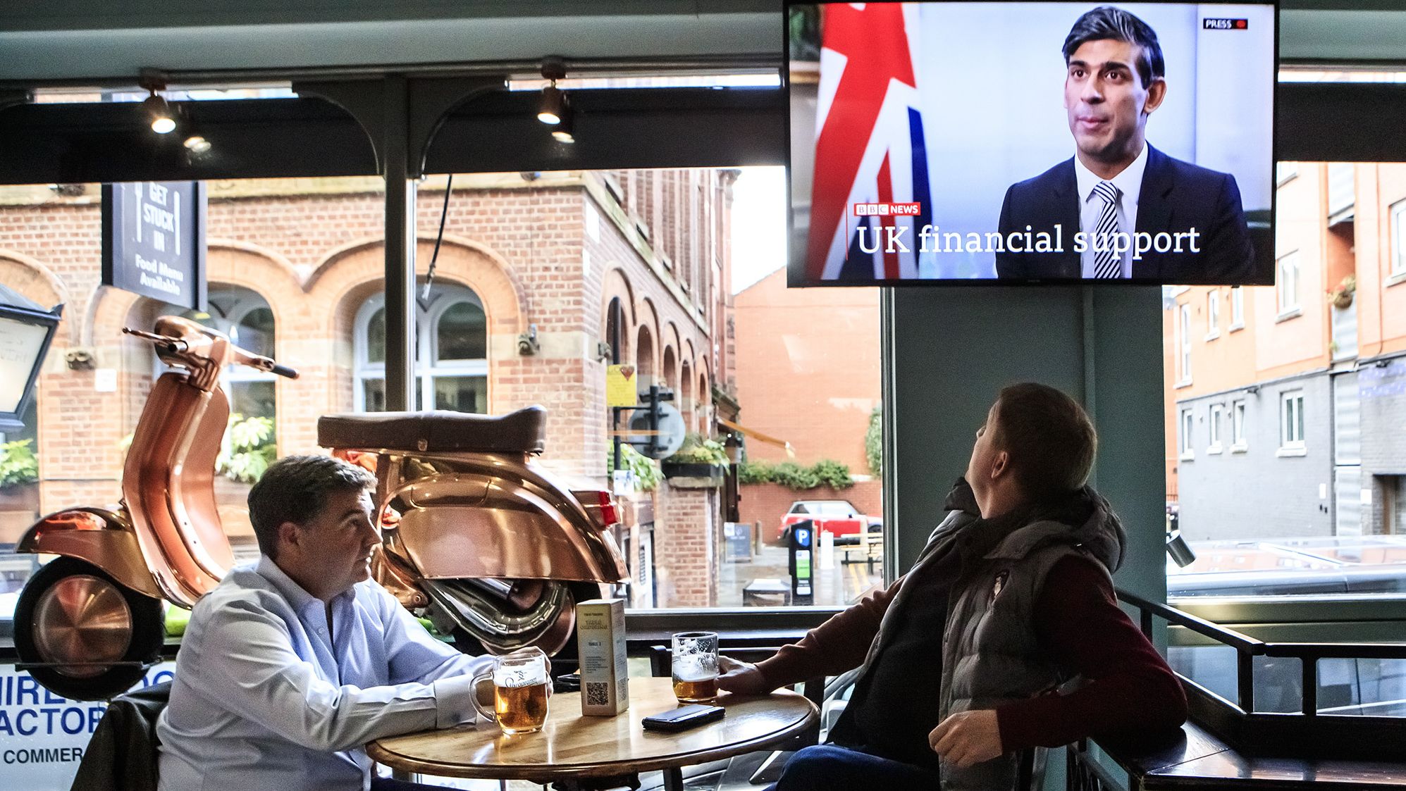 In October 2020, customers at the Tib Street Tavern in Manchester watch Sunak announce that the government will pay two-thirds of staff wages in pubs, restaurants and other businesses if they are forced to close under new coronavirus restrictions.