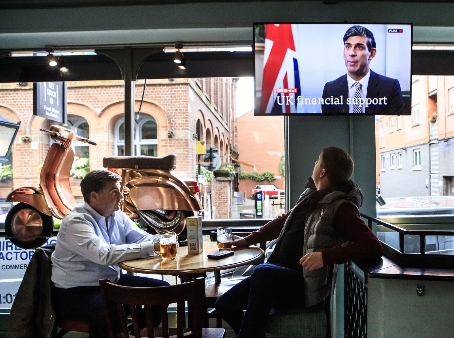 In October 2020, customers at the Tib Street Tavern in Manchester watch Sunak announce that the government will pay two-thirds of staff wages in pubs, restaurants and other businesses if they are forced to close under new coronavirus restrictions.