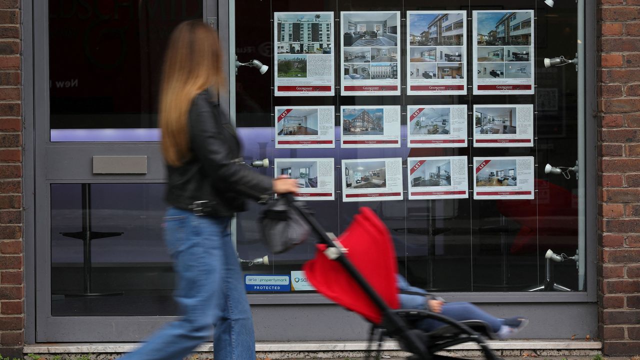 A member of the public looks at residential properties displayed for sale in the window of an estate agents' in London on September 30, 2022. 