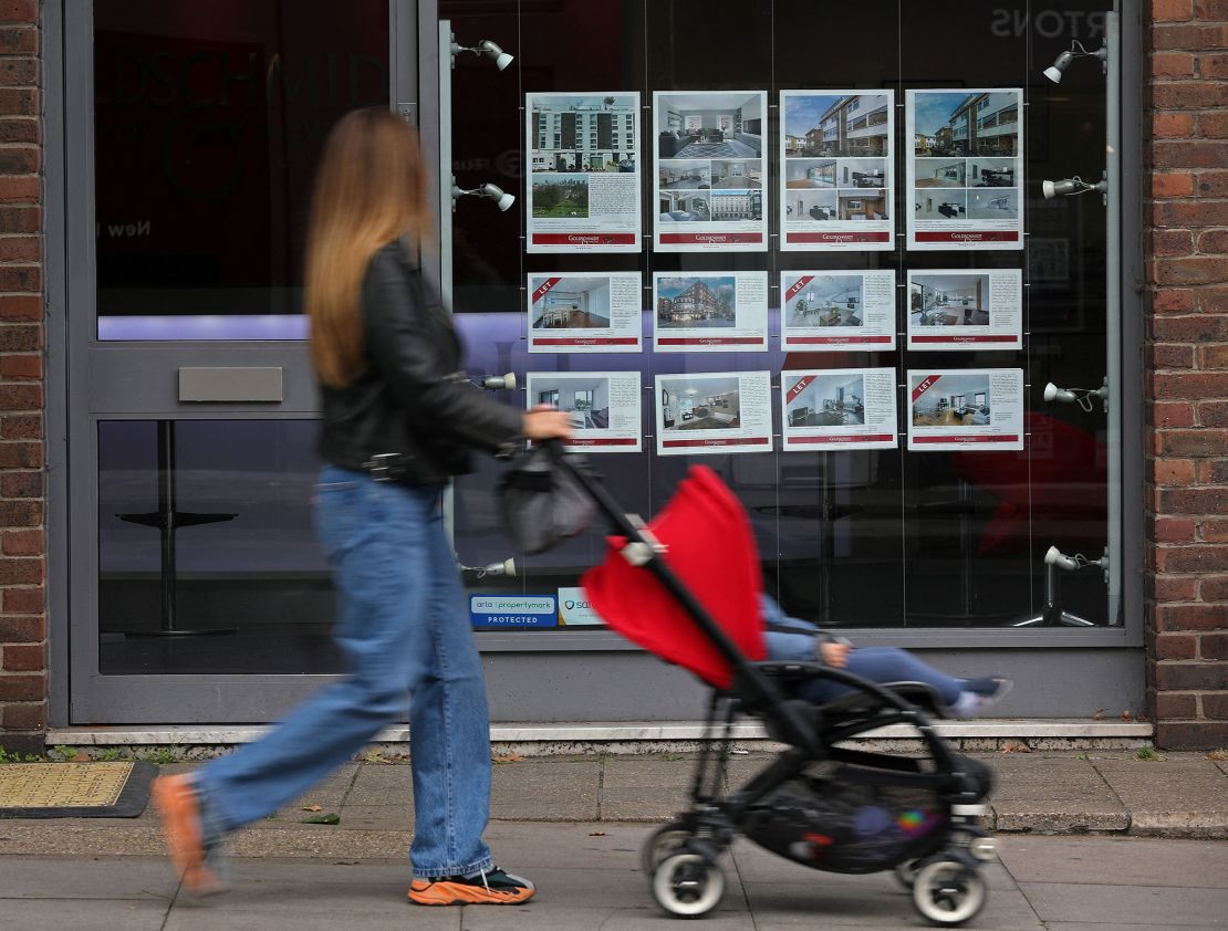 A member of the public looks at residential properties displayed for sale in the window of an estate agents' in London on September 30, 2022. 