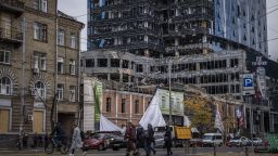 People walk in front of a badly damaged area on October 19, 2022 in Kyiv, Ukraine. Tower 101 is seen in the background which was damaged in a missile strike on October 11, 2022. Recent Russian attacks around Kyiv and across Ukraine have targeted power plants, killing civilians and employees of the key infrastructure.  