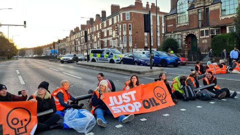 Activists from the Just Stop Oil climate campaign group hold a banner at Barons Court in west London as they block a major road as part of a series of actions on October 18, 2022. 