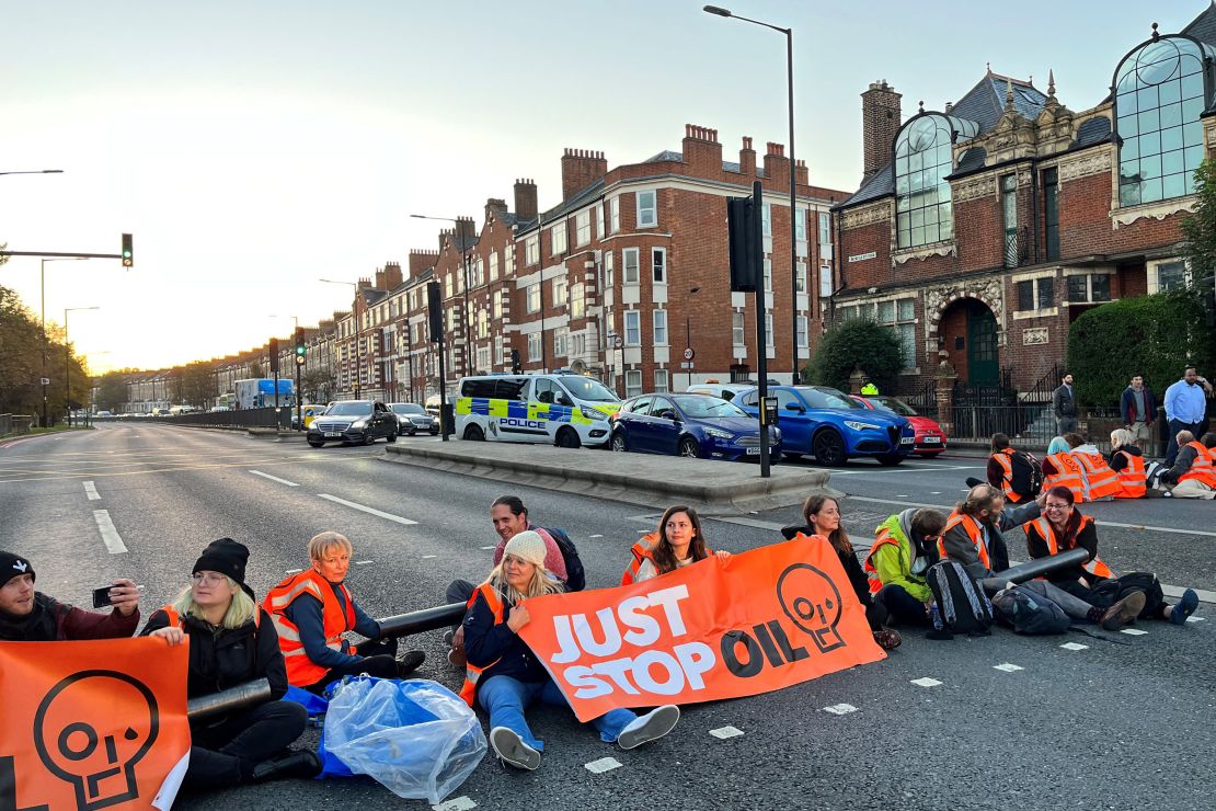 Activists from the Just Stop Oil climate campaign group hold a banner at Barons Court in west London as they block a major road as part of a series of actions on October 18, 2022. 
