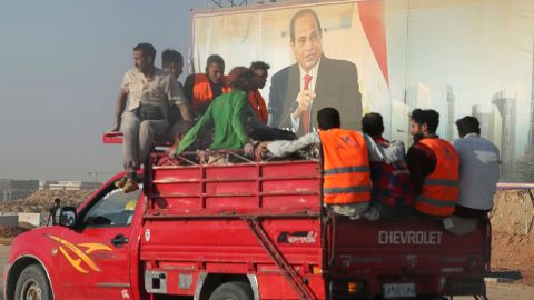 Workers drive past a banner with Egyptian President Abdel Fattah al-Sisi in the New Administrative Capital.