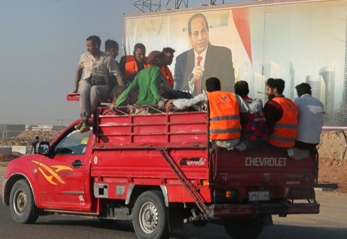 Workers drive past a banner with Egyptian President Abdel Fattah al-Sisi in the New Administrative Capital.