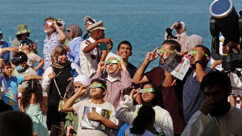 People wearing protective glasses and equipment take a glimpse of a partial solar eclipse in Kuwait City on Tuesday.  