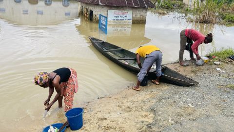 Chigozie Uzo (kiri), seorang pengungsi Odi, di Negara Bagian Bayelsa, Nigeria selatan, membilas ikan mentahnya di air banjir yang kotor, Selasa.