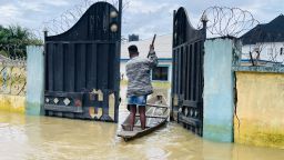 A young woman is pictured paddling her boat through the gate of her flooded house in Odi, in Nigeria's southern Bayelsa State on Tuesday, October 25, 2022 (Nimi Princewill/CNN)