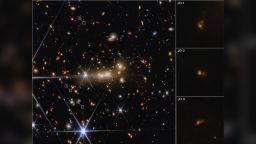 The massive gravity of galaxy cluster MACS0647 acts as a cosmic lens to bend and magnify light from the more distant MACS0647-JD system. It also triply lensed the JD system, causing its image to appear in three separate locations. These images, which are highlighted with white boxes, are marked JD1, JD2, and JD3; zoomed-in views are shown in the panels at right. In this image from Webb's Near Infrared Camera (NIRCam) instrument, blue was assigned to wavelengths of 1.15 and 1.5 microns (F115W, F150W), green to wavelengths of 2.0 and 2.77 microns (F200W, F277W) and red to wavelengths of 3.65 and 4.44 microns (F365W, F444W). 
