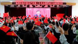 This photo taken on October 16, 2022 shows people waving national flags and Communist Party flags as they watch the opening session of the 20th Chinese Communist Party Congress in Huaibei, in Chinas eastern Anhui province.