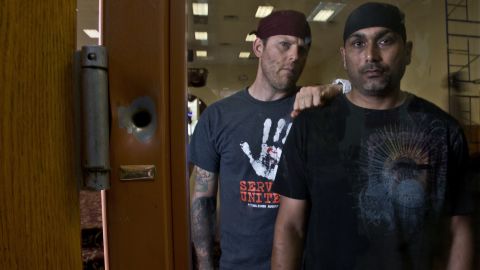 Pardeep Kaleka, right, and Arno Michaelis in 2013 at the Sikh temple in Oak Creek. At left is a bullet hole from the shooting.