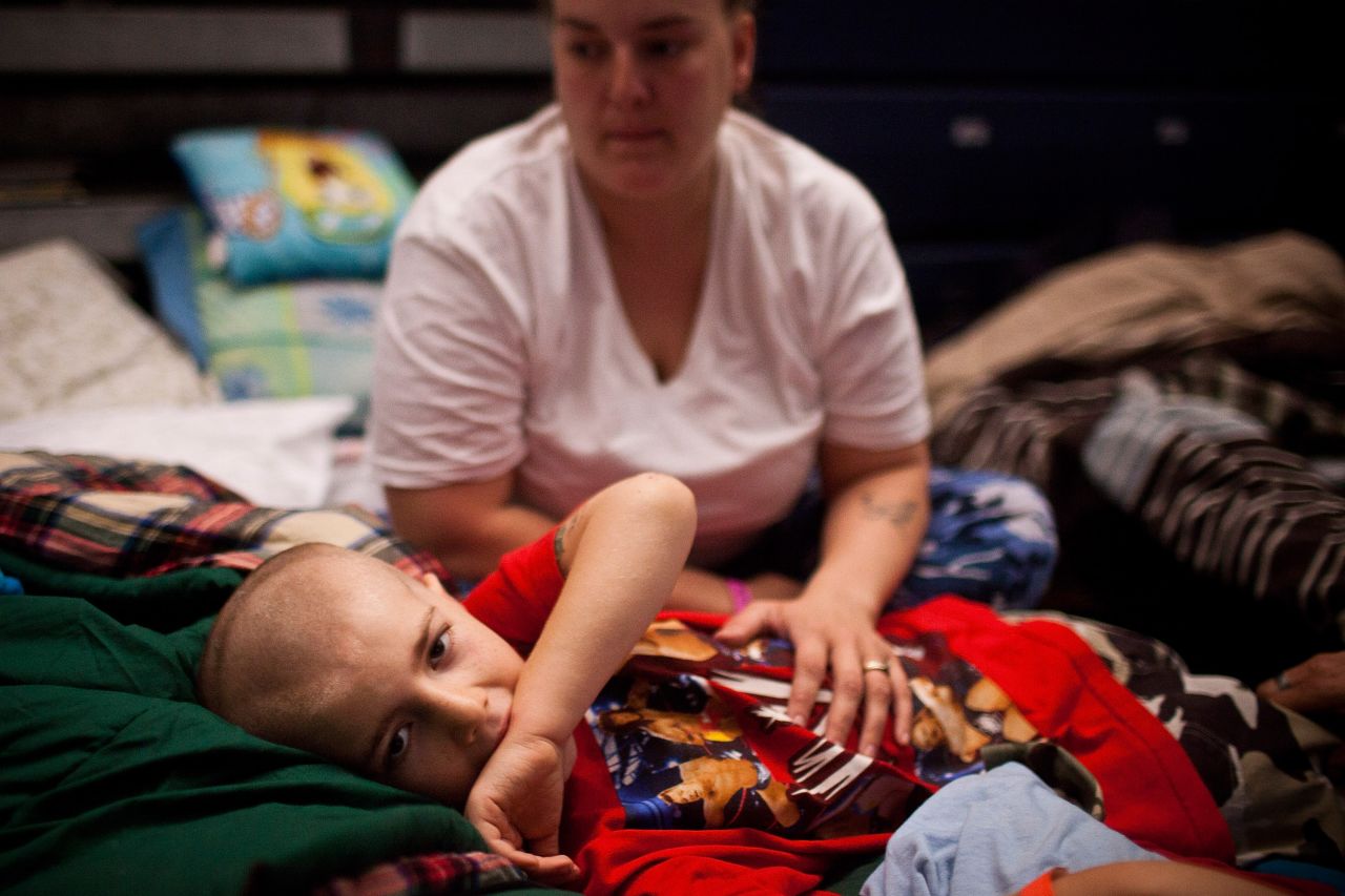 Eight-year-old Michael Fischkelta lays on a cot with his mother, Jenifer Wilson, at a Red Cross evacuation shelter that was set up in a high school gymnasium in Toms River, New Jersey, on November 5, 2012.